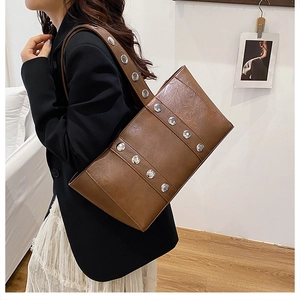 Détail du sac sous le bras en cuir marron avec des rivets métalliques argentés pour femmes