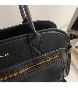 Detail of the black leather handbag showing golden zippers and SHIJIA brand logo