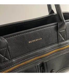 Close-up of black lychee leather crossbody bag with gold zipper and embossed branding