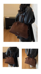 Detail of a large dark brown suede tote bag with sturdy handles and adjustable shoulder strap