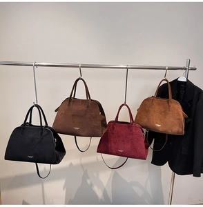 Detail of four matte suede bucket bags in black, burgundy, camel, and dark brown colors