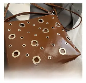 Gros plan du sac en similicuir marron brillant avec détails d'oeillets métalliques