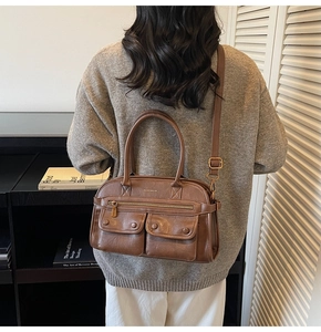 Detail view of a brown faux leather tote bag with decorative pockets and adjustable strap