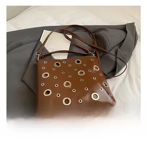 Détails d'un sac en cuir verni marron avec de grands œillets métalliques décoratifs