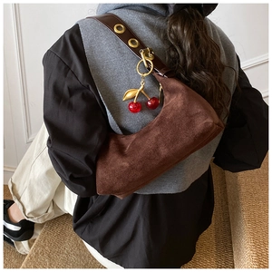 Detail of dark brown suede crescent bag with leather strap and cherry charm detail