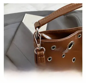 Détail du sac en cuir marron brillant avec mousqueton et œillets en argent