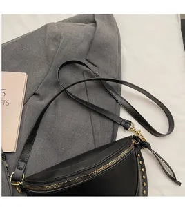Detail of black matte leather half-moon bag with gold rivets and smooth shoulder strap