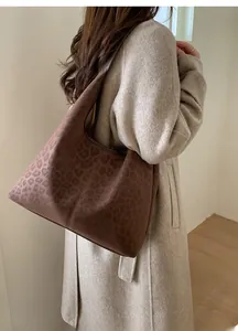 Détail du sac cabas vintage léopard porté avec un manteau beige dans un cadre chaleureux