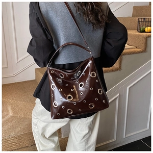 Détail d'un sac en cuir marron foncé brillant avec œillets argentés et vue de profil latéral