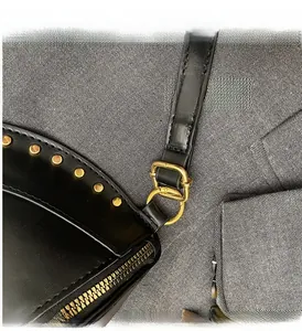 Detailed close-up of golden metal studs and zipper on a black leather half moon bag