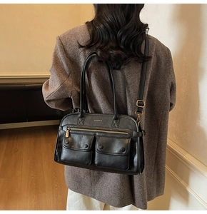 Detail of a black leather tote bag featuring two front flap pockets and versatile straps