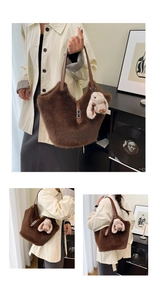 Detail of a large brown plush tote bag with a white rabbit charm and leather buckle strap