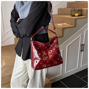 Détail du sac fourre-tout en similicuir bordeaux brillant avec œillets métalliques