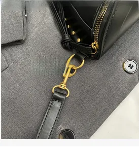 Detail of high-quality gold hardware and studs on a black leather crescent shoulder bag