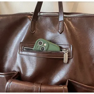 Gros plan de la poche avant zippée sur un sac cabas marron en similicuir avec détails