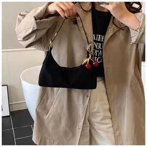 Detail of black suede tote bag featuring a cute metal cherry charm and adjustable strap