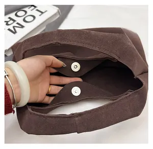 Detail of metal magnetic closure on a large dark brown suede tote bag for women