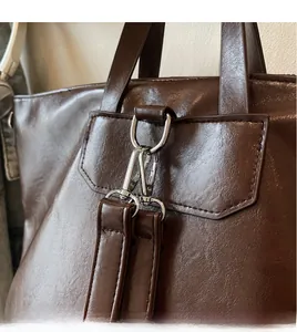 Détail du crochet en métal argenté et double couture sur sac en cuir marron