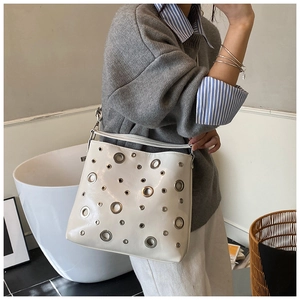 Détail du sac à bandoulière blanc brillant avec œillets métalliques argentés style punk