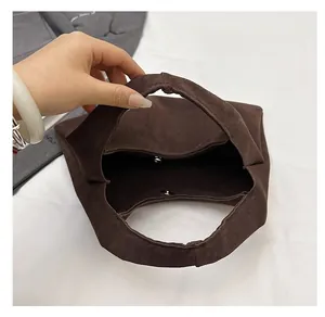 Close-up of a large brown suede tote bag featuring a magnetic clasp and spacious interior