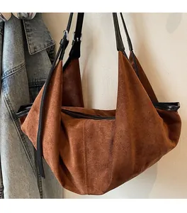 Detail of soft brown suede shoulder bag showing metal buckle and black leather strap