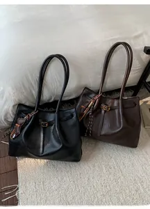 Detail of large tote bags in black and dark coffee leather with stylish tassel accents