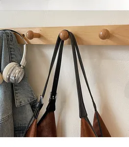 Detail of adjustable slim shoulder strap and metal buckle on brown suede tote bag
