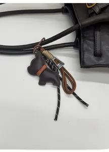 Detail of a dark brown leather tote bag with a French Bulldog leather pendant and charm