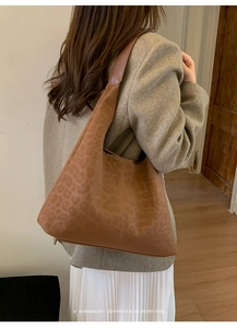 Détail du sac cabas léopard vintage avec bandoulière en cuir marron porté à l'épaule