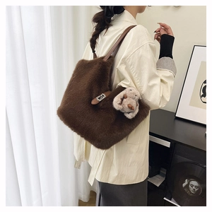 Detail of soft brown plush tote bag with leather strap and cute furry bunny keychain