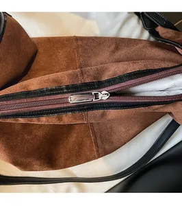 Detail of smooth silver metal zipper on premium brown suede minimalist crossbody bag