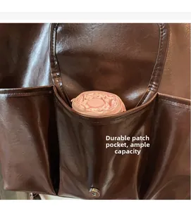 Détail d'un sac à dos en cuir montrant trois poches frontales avec un parapluie rose