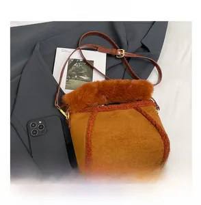 Dettaglio della borsa a secchiello in peluche marrone con logo oro e tracolla in pelle