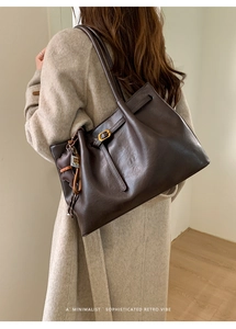 Detail of vintage brown tote bag with cute bear charm and golden metal buckle