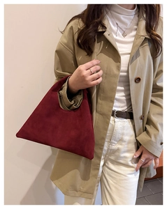 Detail of burgundy suede tote bag with geometric design worn with a beige trench coat