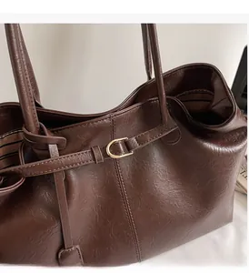 Detailed close-up of dark brown tote bag with high-quality gold hardware accents