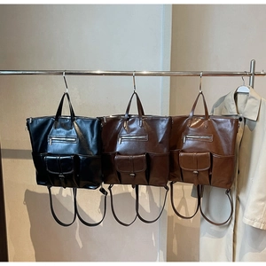 Trois sacs vintage en cuir ciré noir et marron suspendus à un support métallique