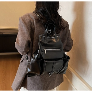 Vue arrière du modèle portant un grand sac à dos en similicuir noir avec poches zippées