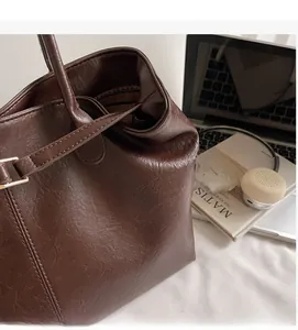 Close-up of coffee brown leather tote bag with lychee texture and thin shoulder strap