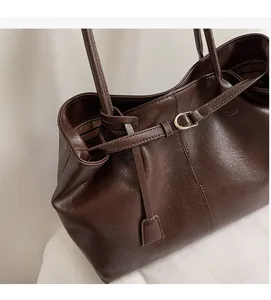 Close-up of deep brown tote bag featuring fine pebble leather texture and metal buckle