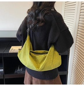 Green suede crescent tote bag showing the adjustable strap on model's shoulder