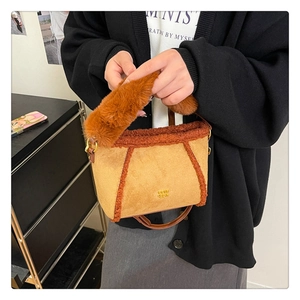 Dettaglio della borsa in finto camoscio marrone con bordo in peluche e logo dorato DPIH