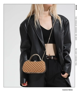 Detail of vintage polka dot box bag with gold metal handle and chain strap for women
