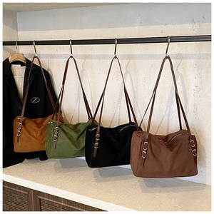 Detail view of large suede shoulder bags in caramel, olive, black, and coffee colors