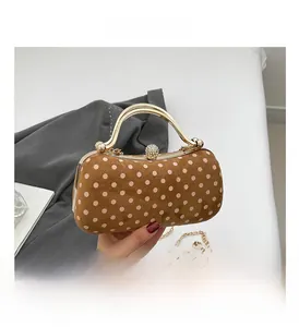 Close-up of vintage brown polka dot suede clutch bag with gold metal frame and chain strap