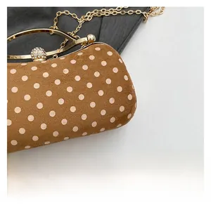 Detailed view of brown polka dot evening clutch with gold rhinestones clasp and chain