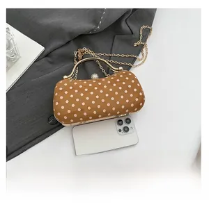 Brown suede clutch bag with white polka dots and gold chain strap shown next to phone