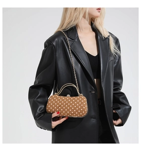 Detail of vintage brown polka dot clutch with gold metal handle and chain strap