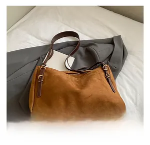 Detail of brown faux suede shoulder bag with adjustable leather strap and metal buckle