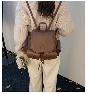 Detail of a brown vintage leather backpack with drawstring closure and metal buckle